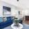 Spacious and well lit living room with wood floors and a large window with access to the kitchen
